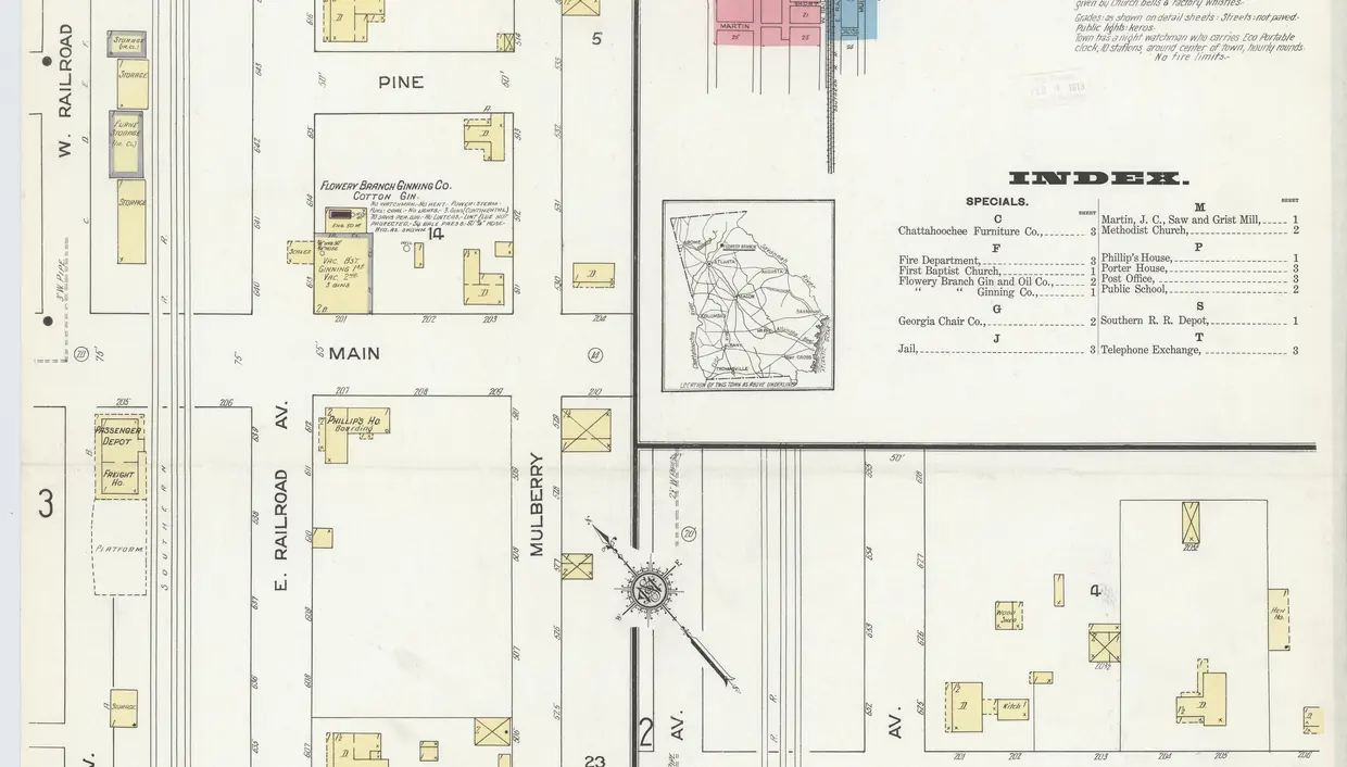 A hand-coloured 1912 fire-insurance map: parallel rail lines between West and East Railroad Avenue, crossed by Chestnut, Pine and Main streets, with the passenger depot beside the tracks.