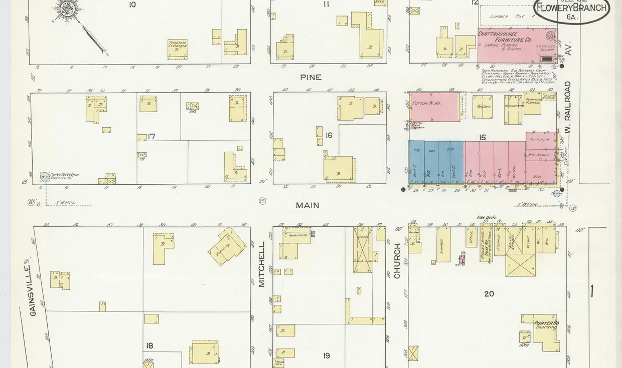 A 1912 fire-insurance map sheet showing town blocks around Main Street and West Railroad Avenue, with a row of pink and blue commercial buildings and small yellow house footprints.